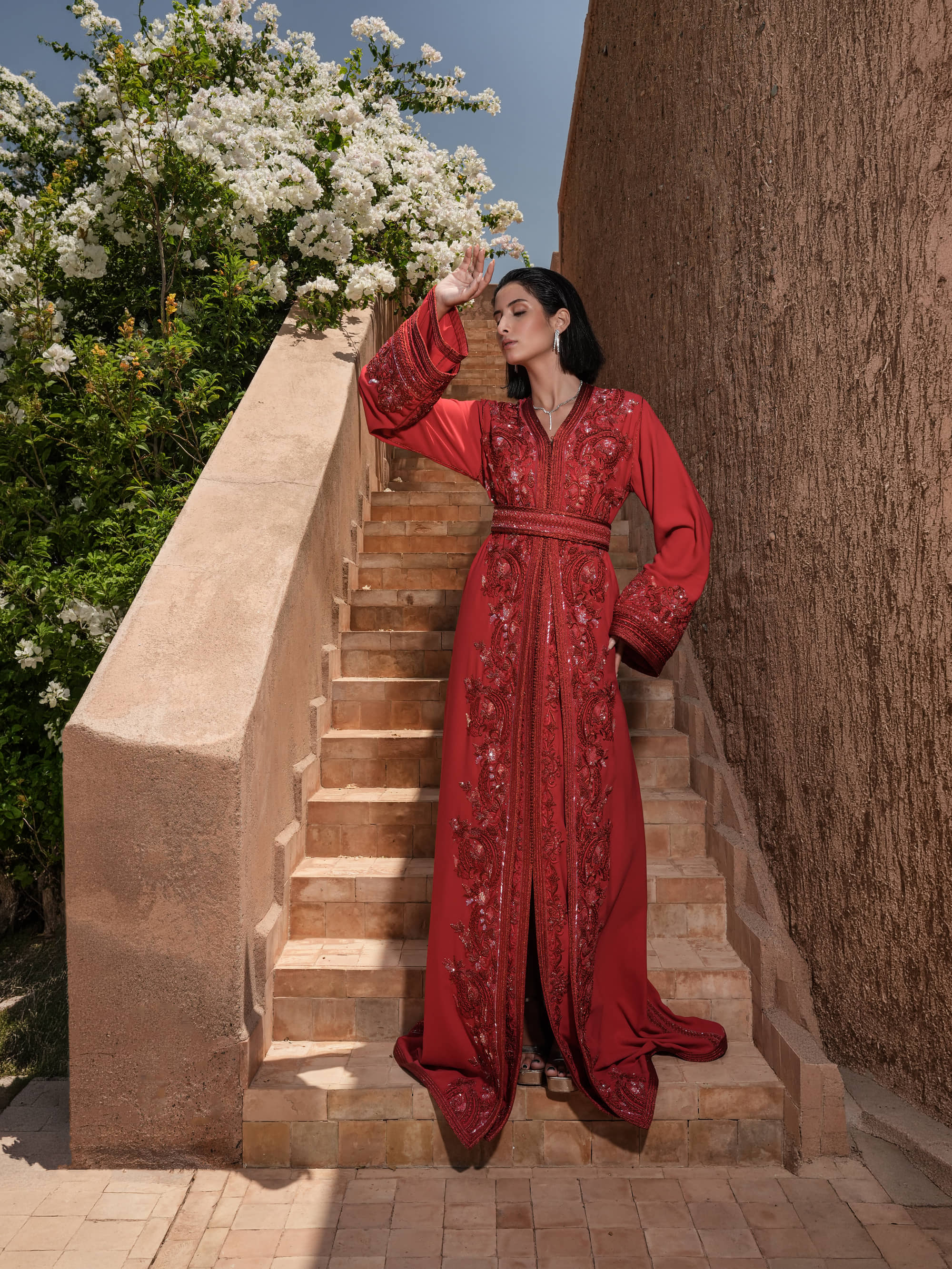 Carmine Cadence red crepe Moroccan kaftan with sequined paisley embroidery, braided belt and flared sleeves, full-length view