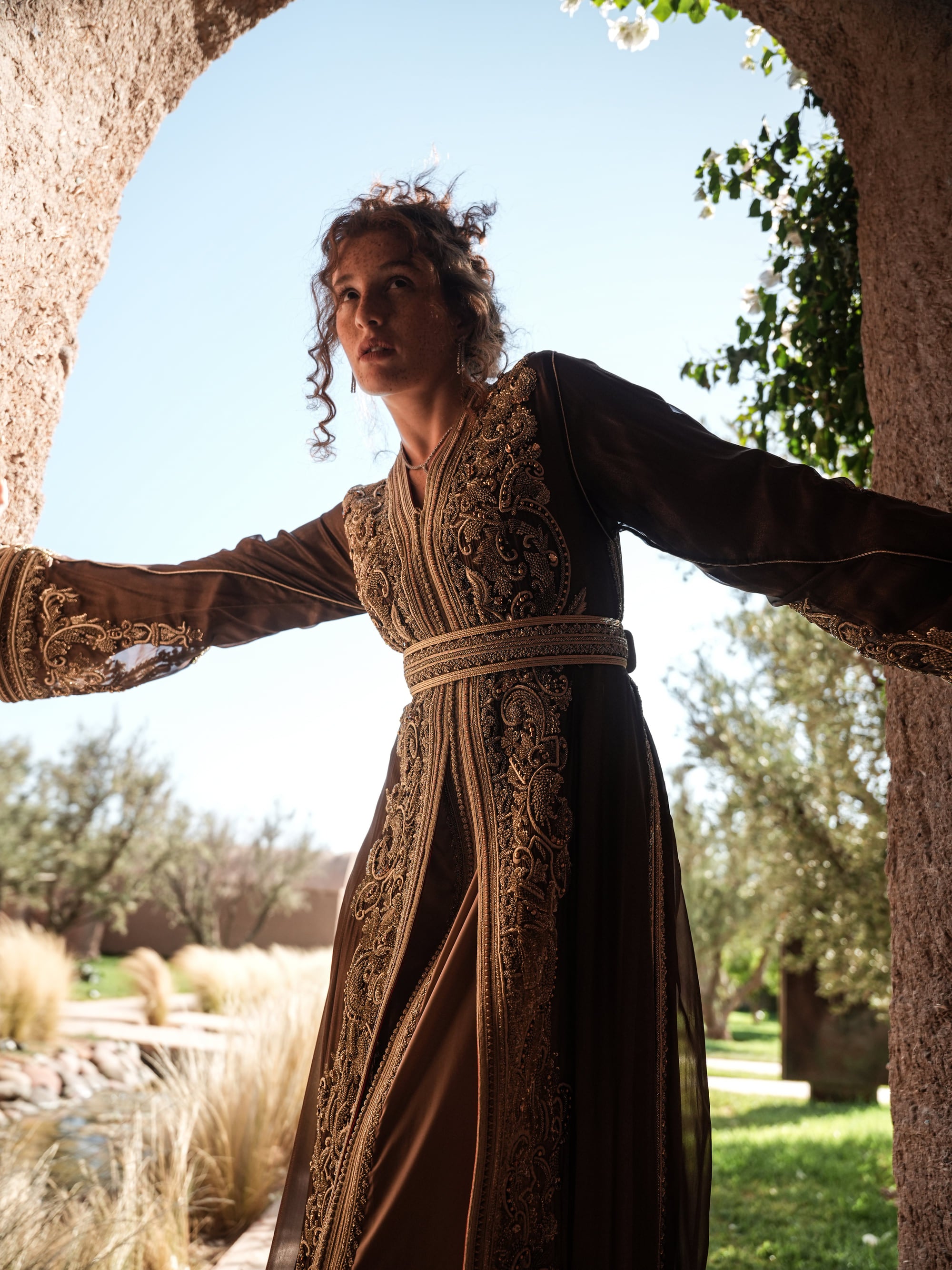 Bronze Reverie lamé organza Moroccan kaftan with gold embroidery, worn open over a champagne dress
