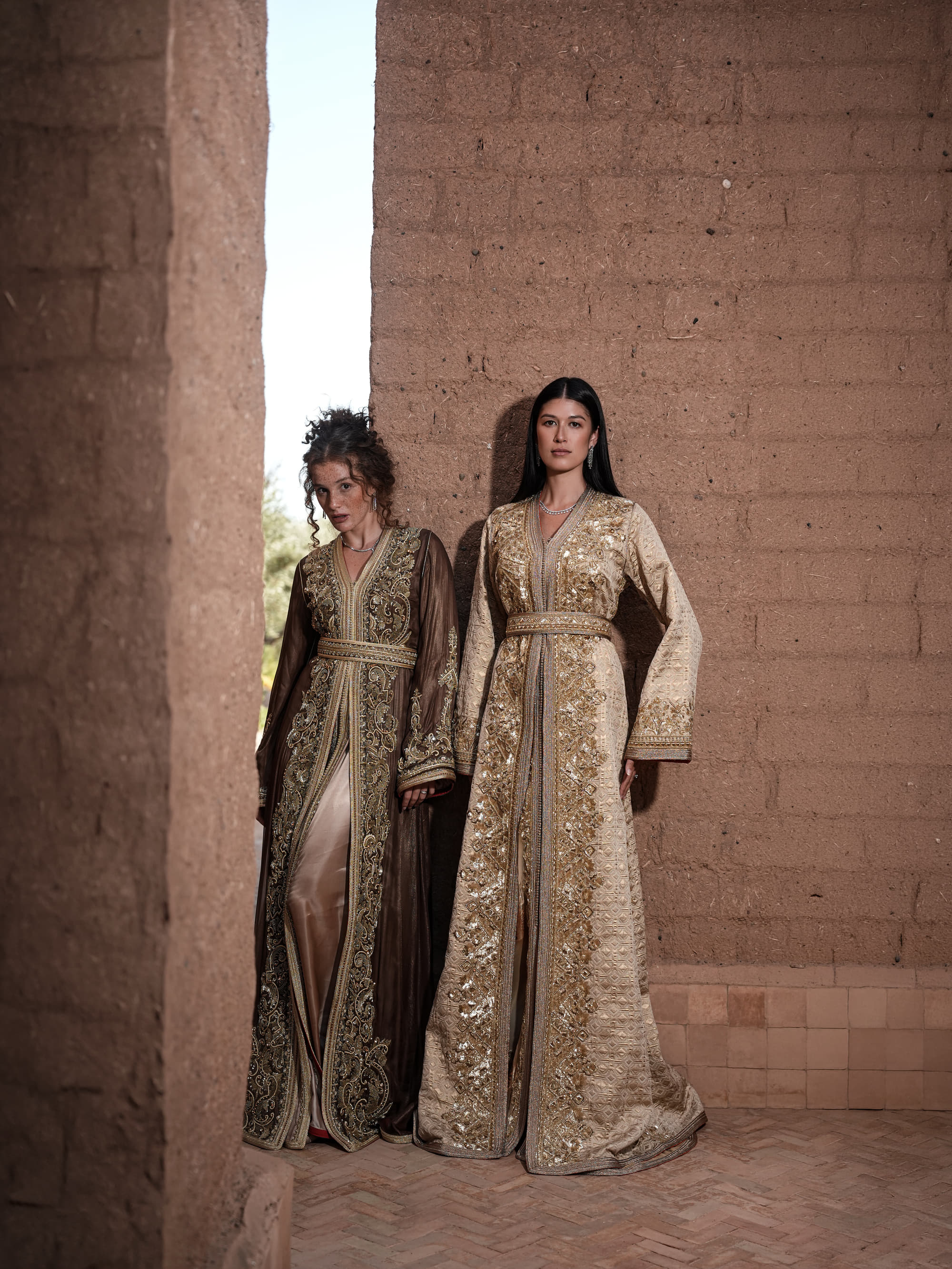 Bronze Reverie lamé organza Moroccan kaftan with gold embroidery, worn open over a champagne dress, shown alongside a second look