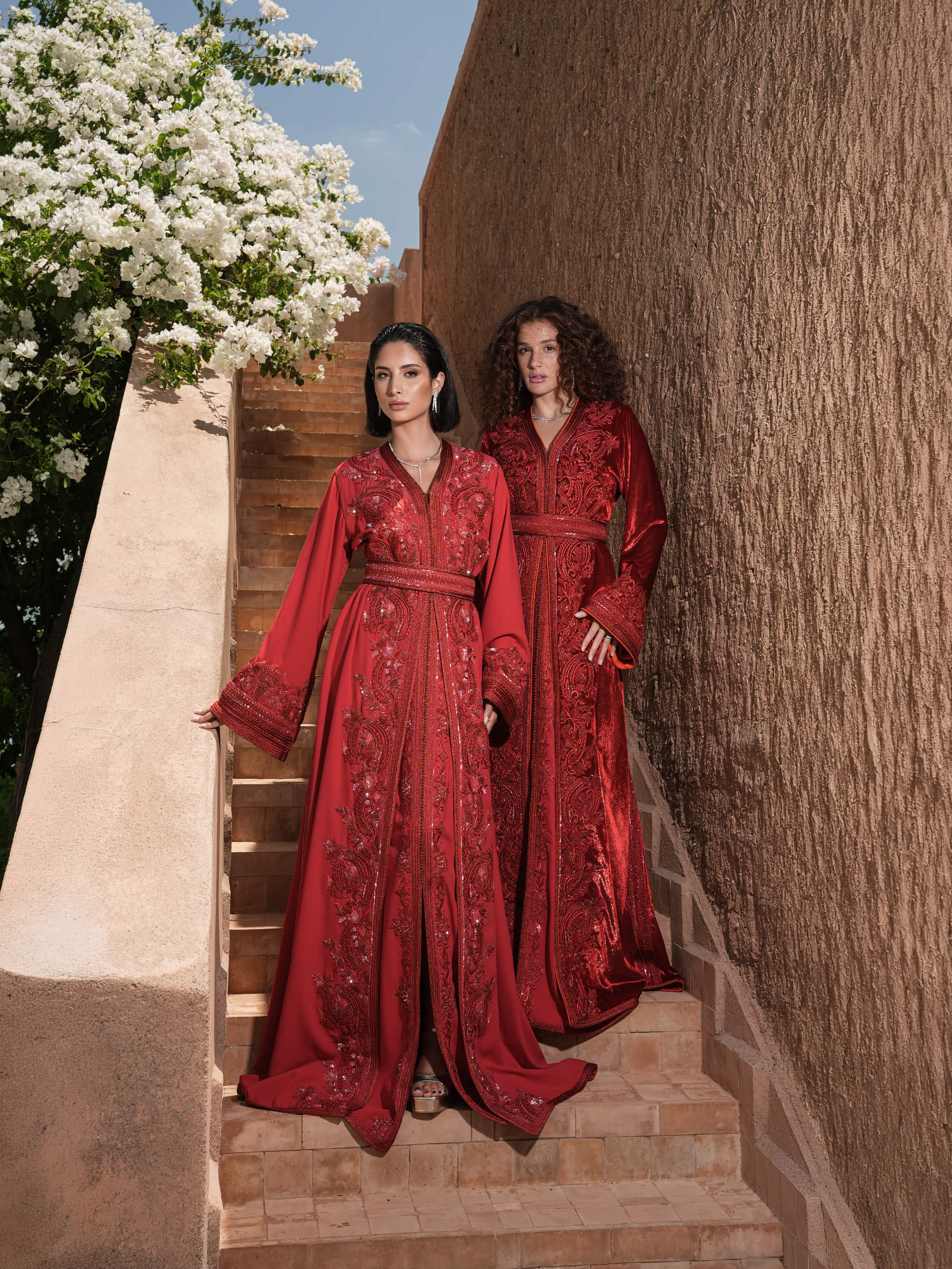 Garnet Adagio burgundy velvet Moroccan kaftan with tone-on-tone embroidery, matching belt and wide sleeves, shown alongside a second look