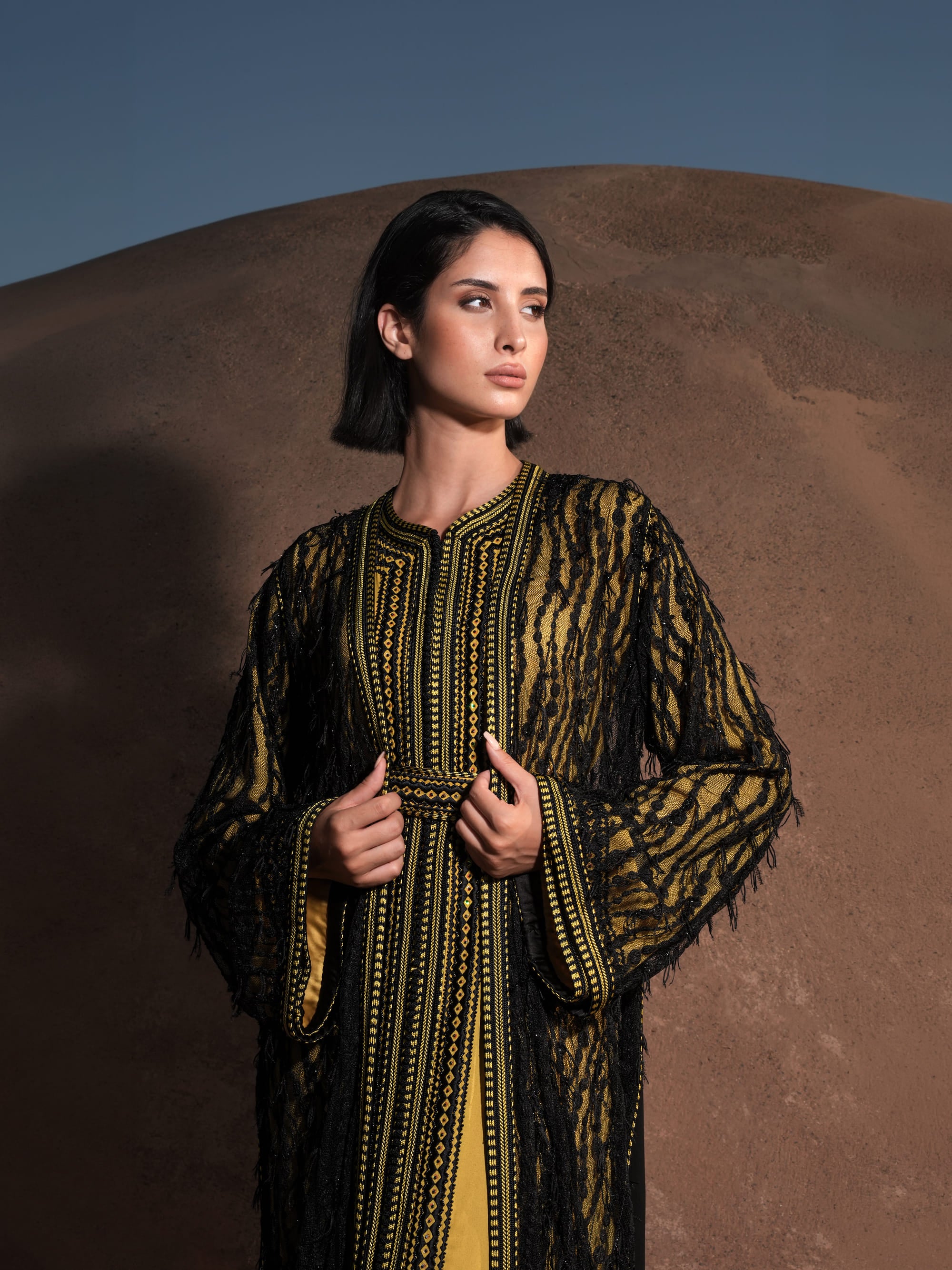 Onyx Serenade fringed black lace Moroccan kaftan over a mustard-gold dress