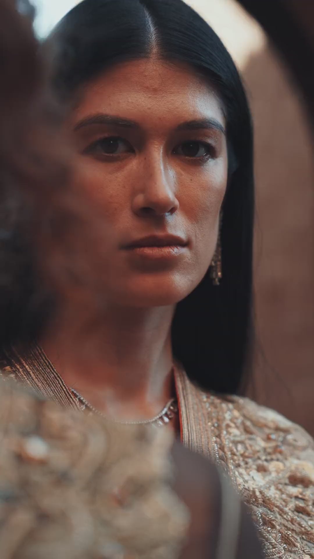 Bronze Reverie lamé organza Moroccan kaftan with gold embroidery, worn open over a champagne dress, in motion