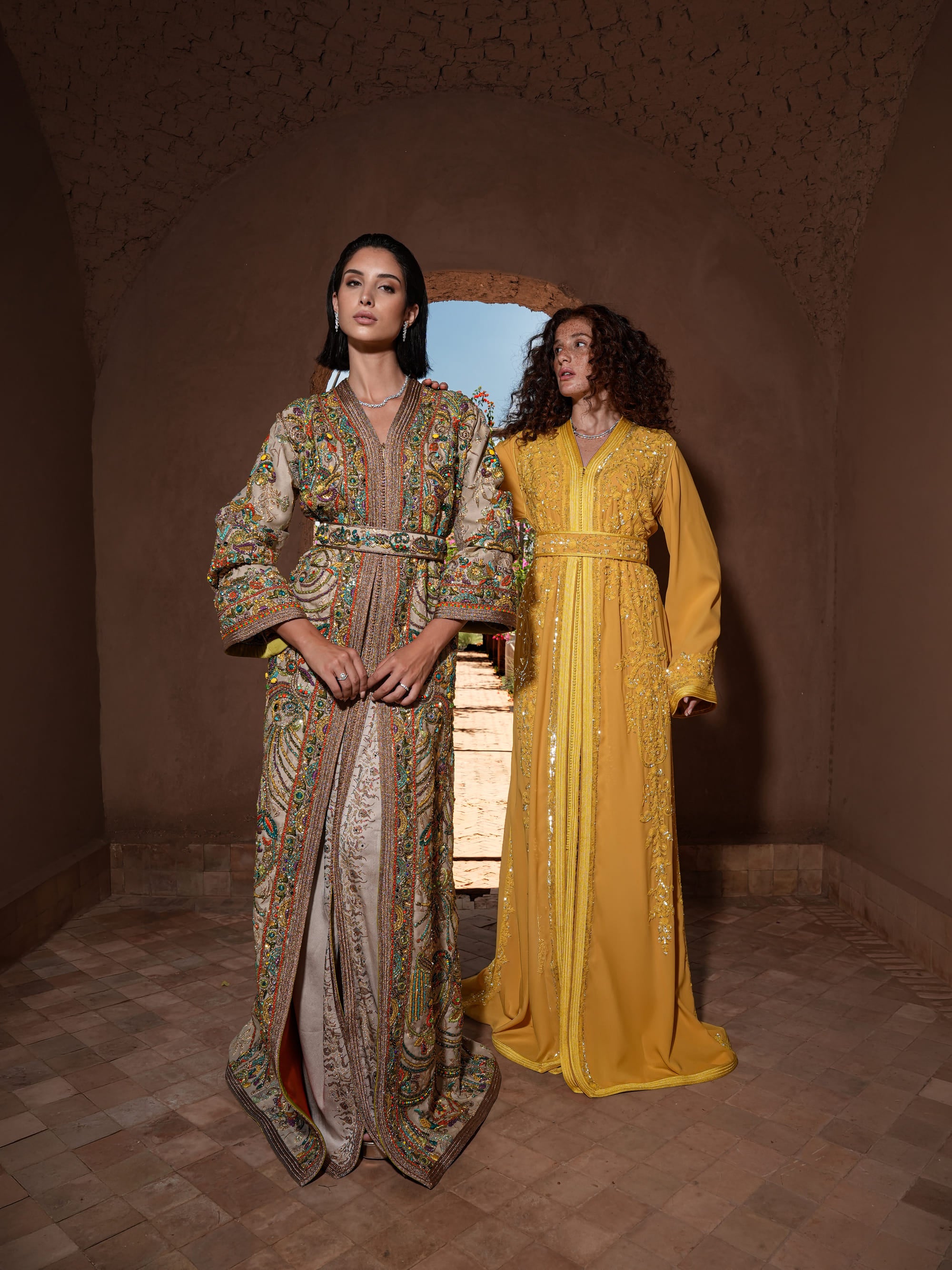 Saffron Vespers saffron crepe Moroccan kaftan with gold and silver embroidery, shown alongside a second look